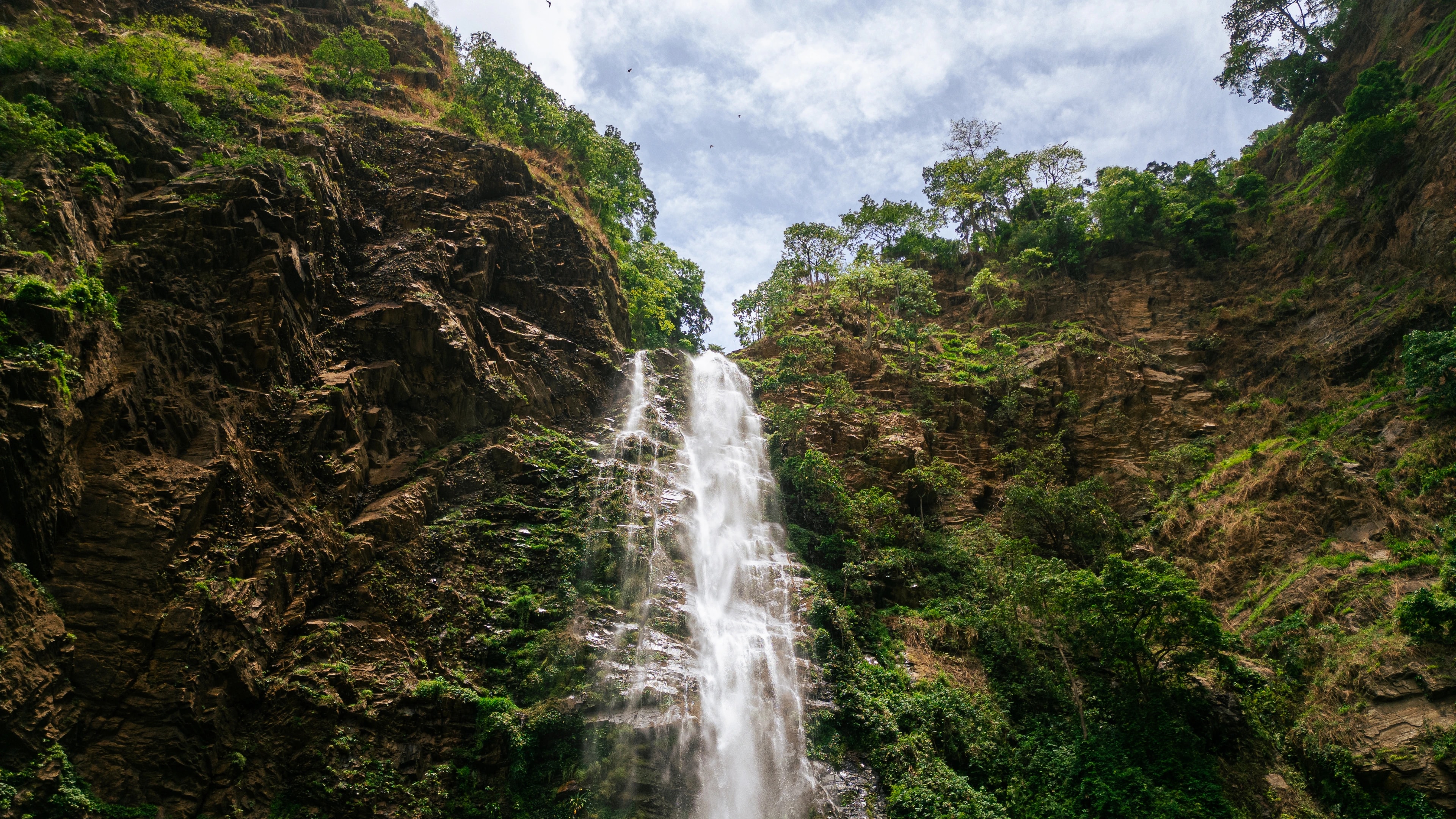 An aerial view of a waterfall surrounded by lush green forest in Ghana